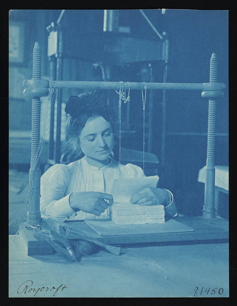 [Interior of bindery with woman worker binding book at table, facing…, New York, East Aurora, 1900