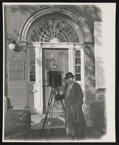 [Frances Benjamin Johnston with large tripod camera, in front of the…, 1936
